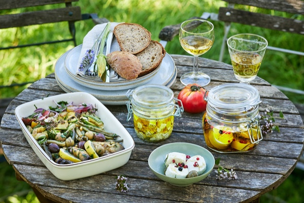 Sommerliches Picknick auf rustikalem Holztisch mit Salat, Brotscheiben, Oliven&ouml;l, Wasser und Wei&szlig;wein, Foto: Oliver Giel