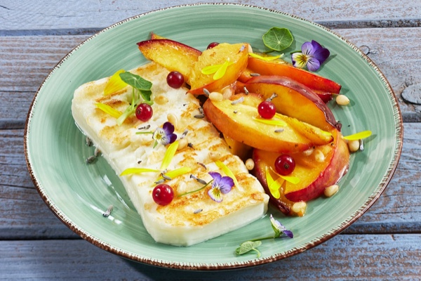 Gegrillter Ziegenk&auml;se mit Pfirsich, roten Johannisbeeren und essbaren Bl&uuml;ten auf Teller, Foto: Oliver Giel