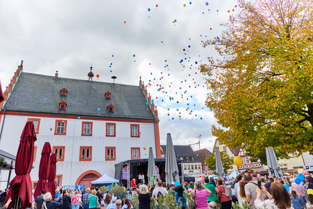 Bunte Luftballons steigen &uuml;ber Menschenmenge vor historischem Geb&auml;ude, Ha&szlig;furter Stra&szlig;enfest, Foto: Oliver Giel