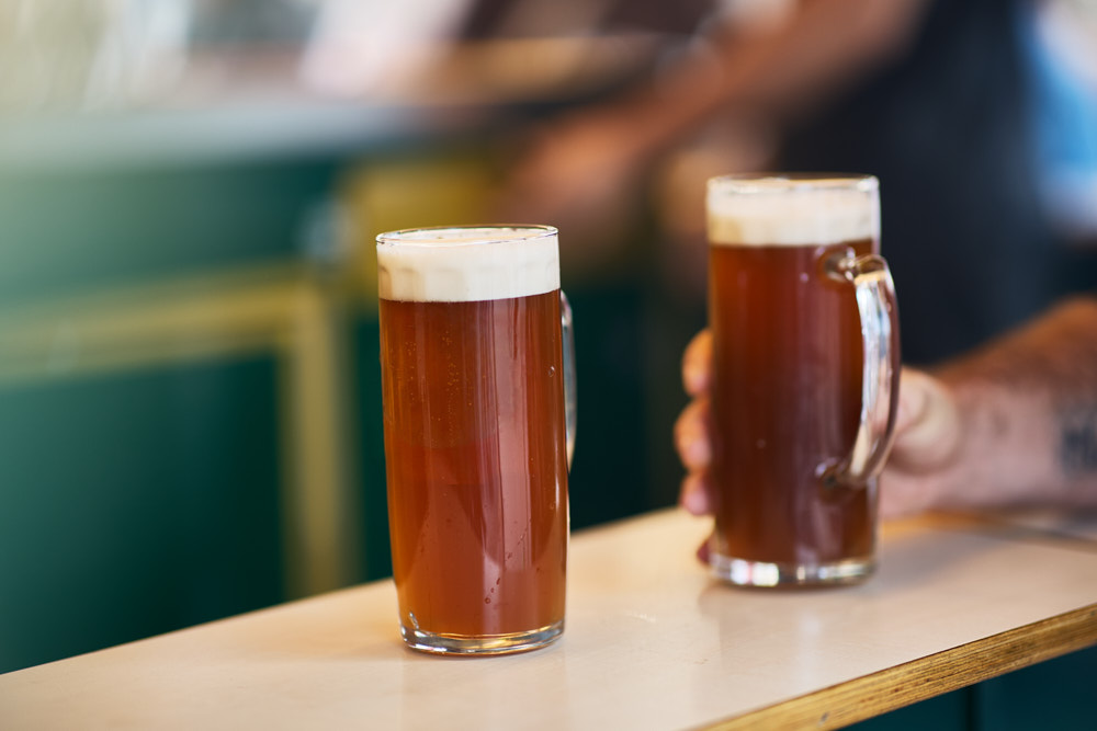 Zwei Biergl&auml;ser mit Henkel auf einem Tresen, Hand im Hintergrund, Ha&szlig;furter Stra&szlig;enfest, Oliver Giel