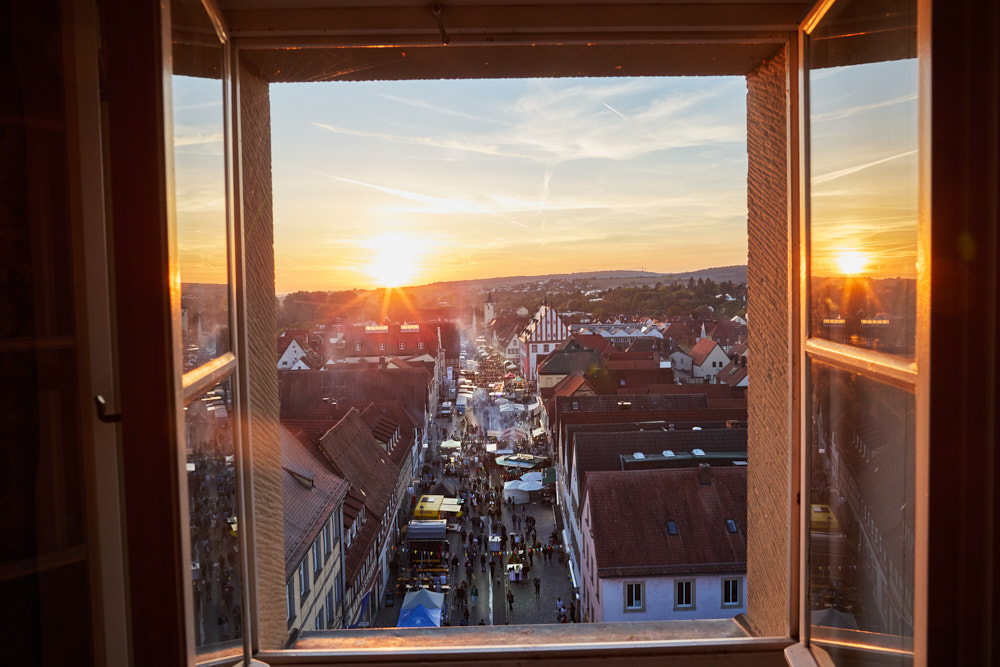 Blick aus offenem Fenster auf belebte Gasse mit St&auml;nden bei Sonnenuntergang, Stra&szlig;enfest Ha&szlig;furt, Oliver Giel