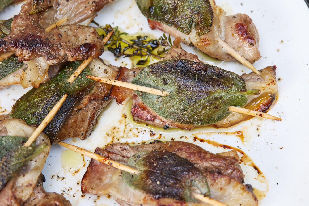 Saltimbocca vom Lamm auf wei&szlig;em Teller mit Salbeibl&auml;ttern und Zahnstocher