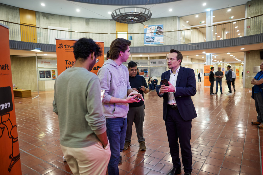 Tag der Wissenschaft in Schweinfurt, Besucher und Moderator in moderner Halle im Gespr&auml;ch, Foto: Oliver Giel